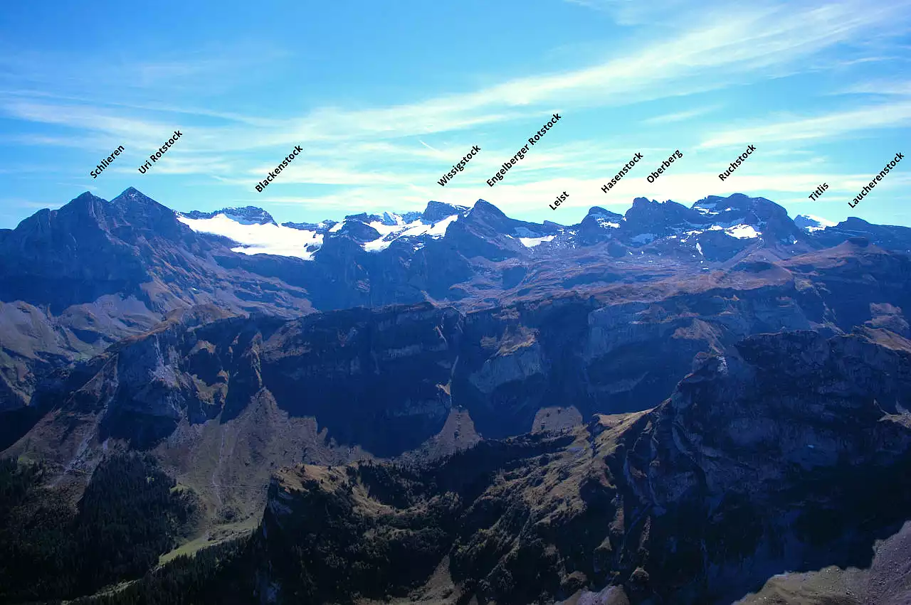 Auf dem Bild geht der Blick vom Risetenstock Richtung Süden zu den Bergen zwischen Uri Rotstock und Ruchstock. Es ist eine interessante Gruppe mit kleinen Gletschern, zwischen Vierwaldstättersee und Engelberg, zwischen Voralpen und Hochalpen. Die bedeutendsten Gipfel sind auf dem Bild beschriftet. Rechts am Bildrand schaut der Titlis bei Engelberg herüber. Der Himmel ist blau, es hat wenige Schleierwolken.